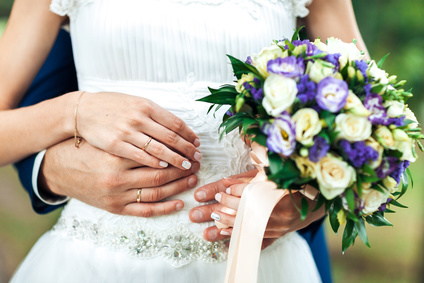 closeup, hands of bride and groom with wedding rings and bouquet